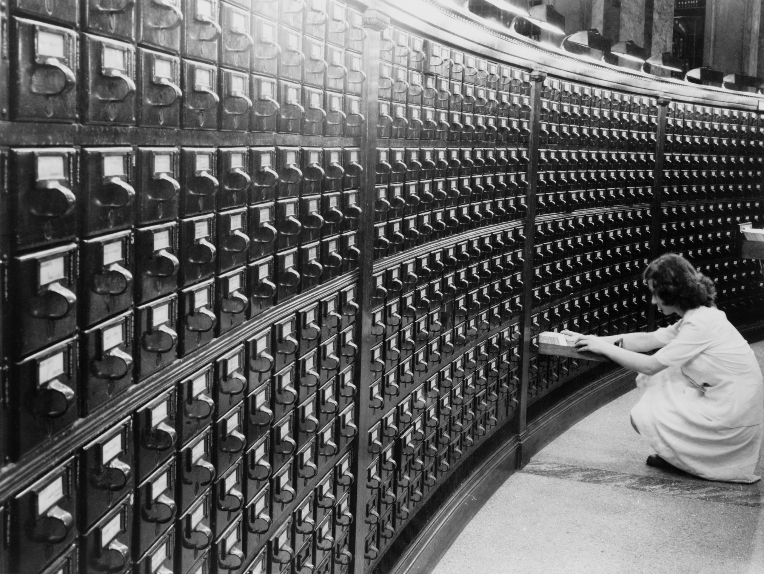Woman using a card catalog in black and white