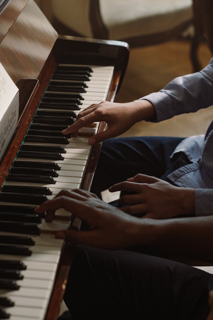 Two individuals playing piano together in a close-up shot, focusing on their hands and the musical keys.